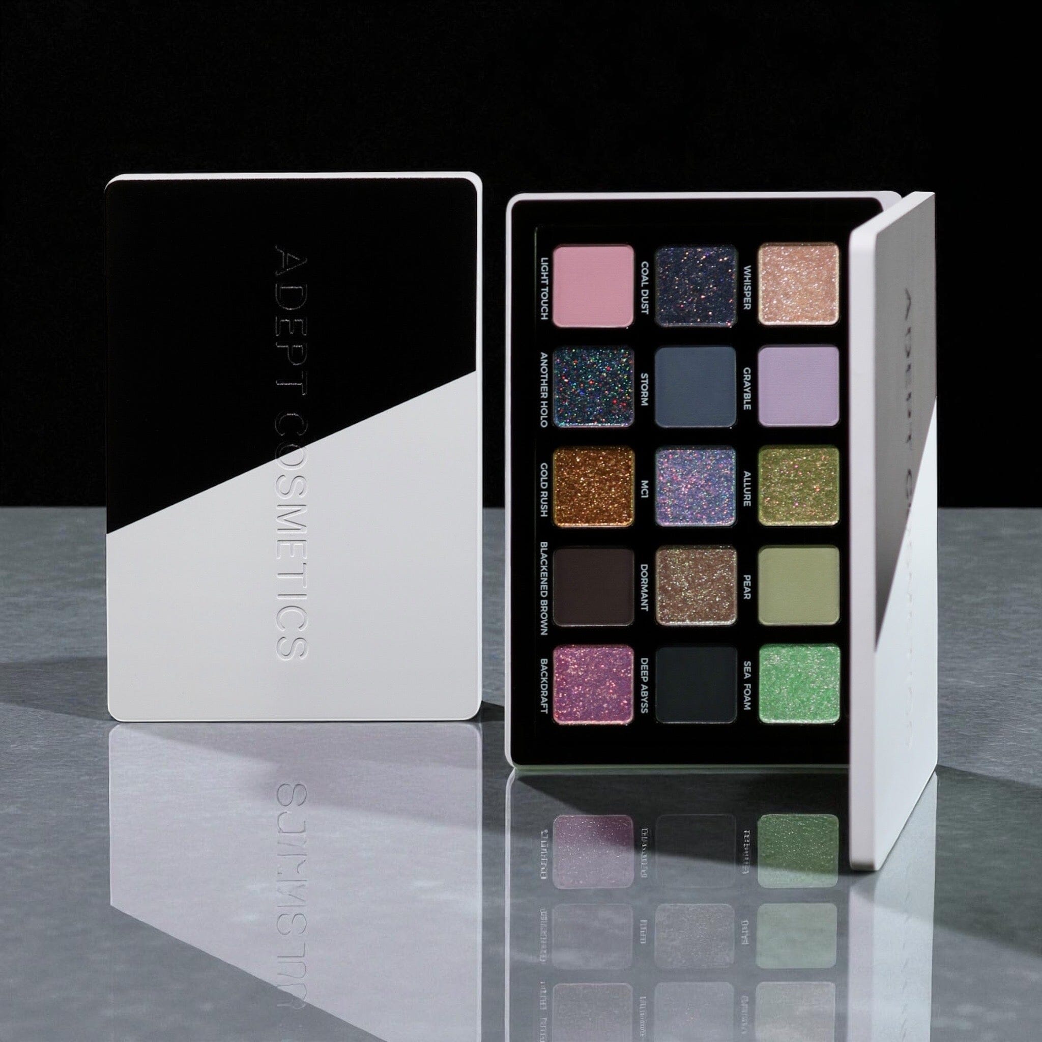 Makeup palette with color swatches and 'Adept Cosmetics' branding on a reflective surface.