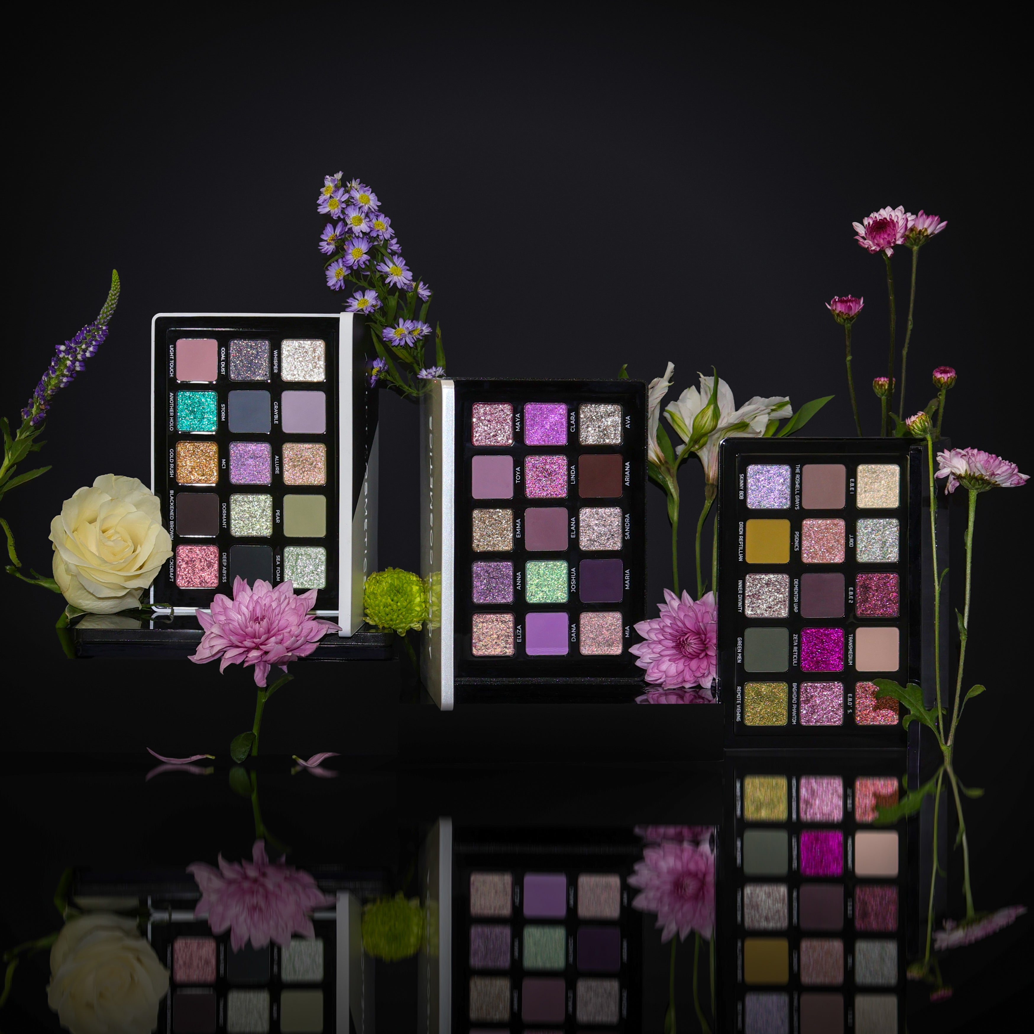 Makeup palettes with colorful shades surrounded by flowers on a black background